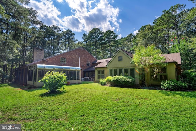 rear view of property featuring a sunroom and a lawn