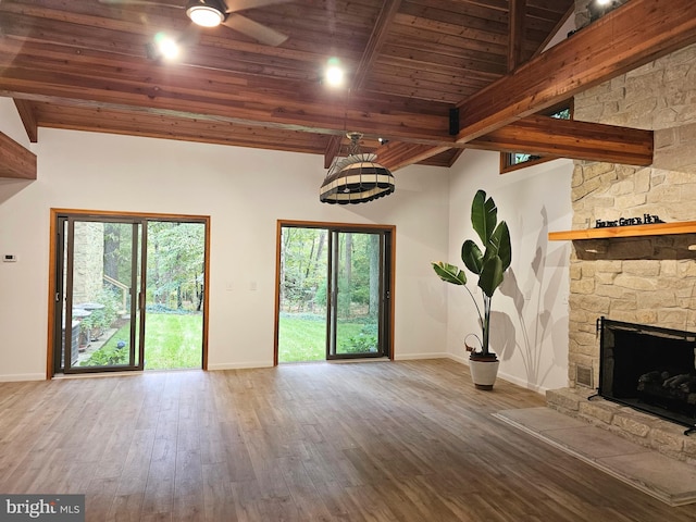 unfurnished living room with vaulted ceiling with beams, ceiling fan, a fireplace, wood ceiling, and dark hardwood / wood-style flooring