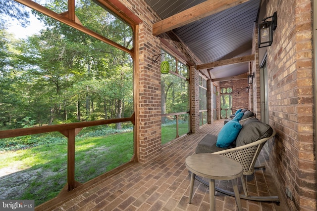 unfurnished sunroom featuring vaulted ceiling with beams