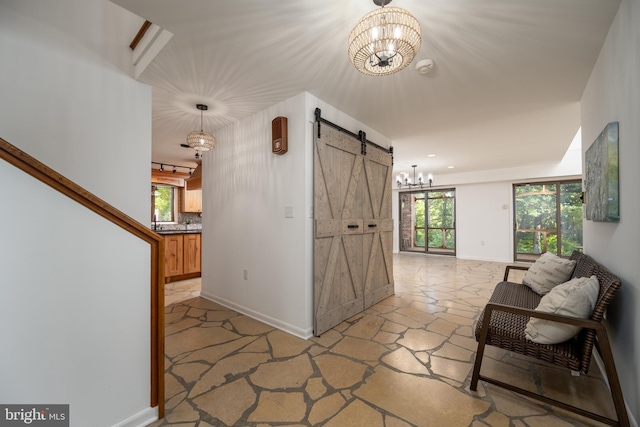 hall featuring a barn door, a notable chandelier, a healthy amount of sunlight, and light tile floors