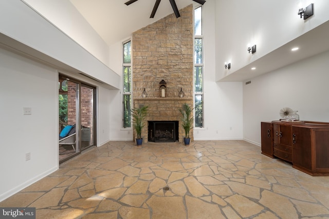 unfurnished living room featuring high vaulted ceiling, ceiling fan, and a stone fireplace