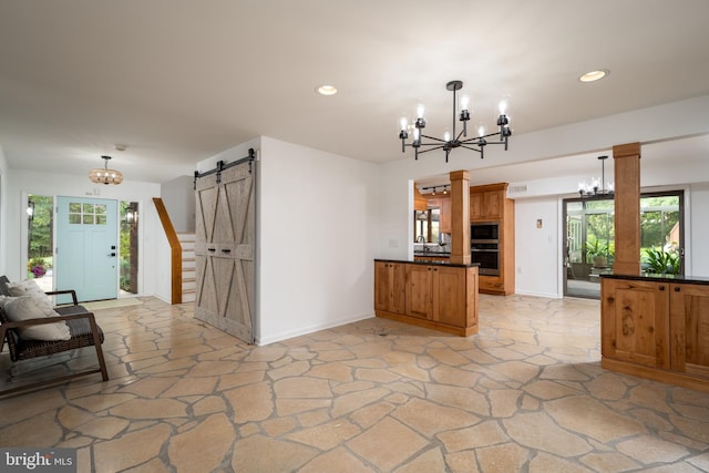 kitchen with a barn door, a wealth of natural light, pendant lighting, and an inviting chandelier