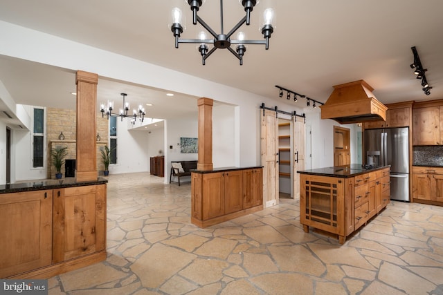 kitchen with hanging light fixtures, backsplash, track lighting, a notable chandelier, and stainless steel refrigerator with ice dispenser