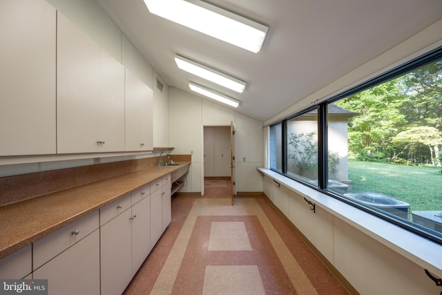 interior space with white cabinets, lofted ceiling, and sink