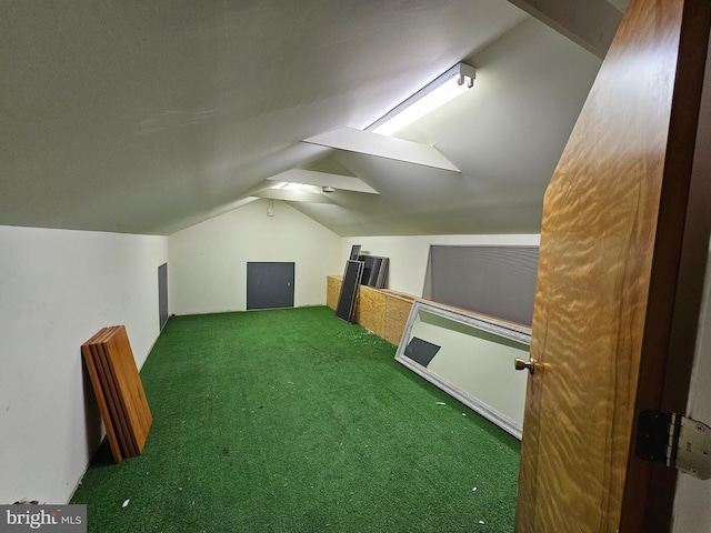 additional living space featuring dark carpet and vaulted ceiling