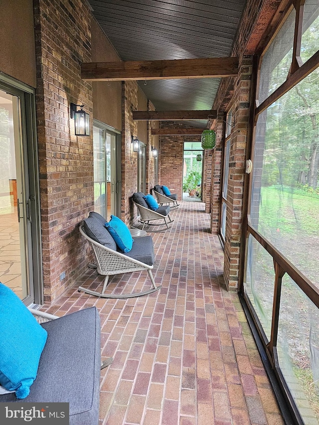 unfurnished sunroom with vaulted ceiling with beams