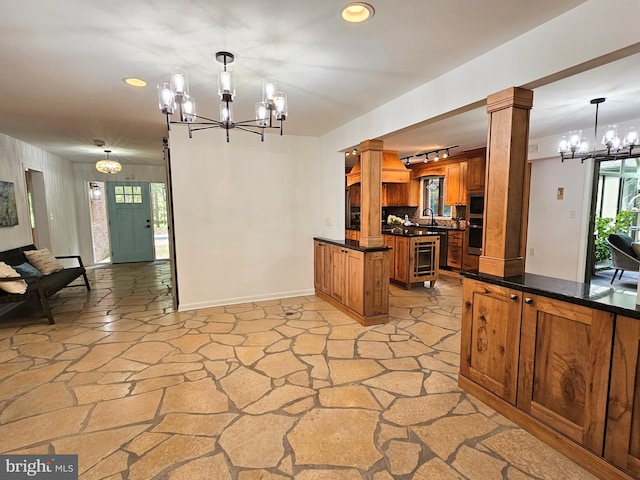 kitchen featuring pendant lighting, tasteful backsplash, decorative columns, and a notable chandelier