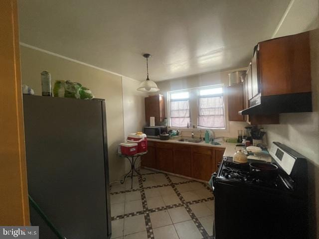 kitchen with sink, light tile floors, black stove, refrigerator, and pendant lighting