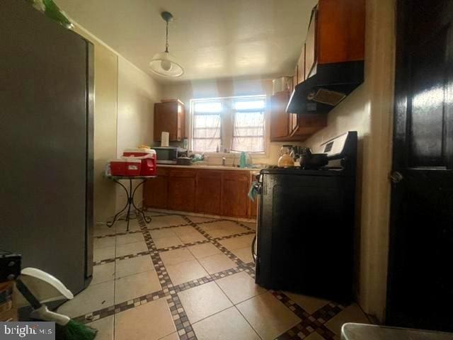 kitchen featuring range, light tile floors, exhaust hood, pendant lighting, and stainless steel fridge