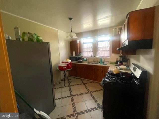 kitchen featuring light tile floors, decorative light fixtures, refrigerator, black range oven, and sink