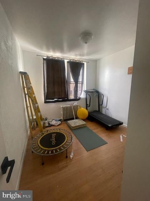 exercise room featuring radiator heating unit and hardwood / wood-style flooring