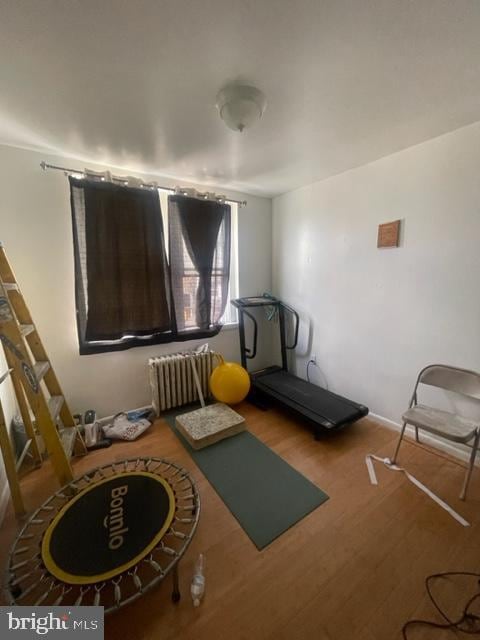 workout room featuring wood-type flooring and radiator heating unit