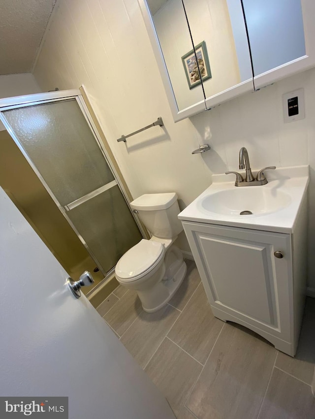 bathroom featuring an enclosed shower, tile floors, vanity, toilet, and a textured ceiling