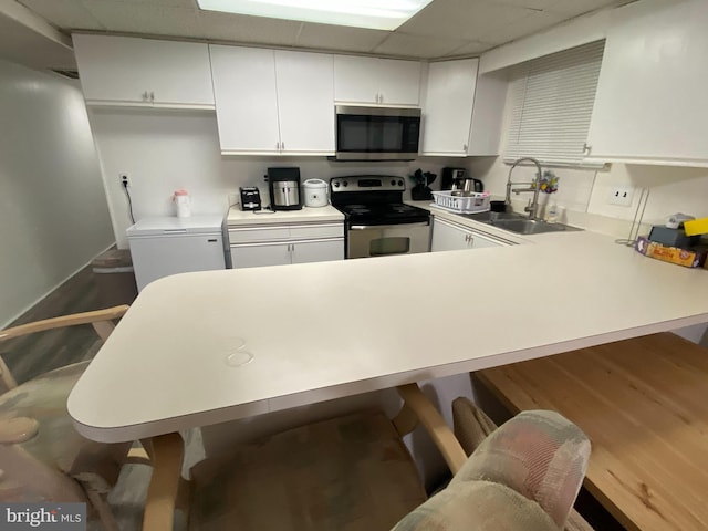 kitchen with kitchen peninsula, appliances with stainless steel finishes, white cabinets, and a breakfast bar