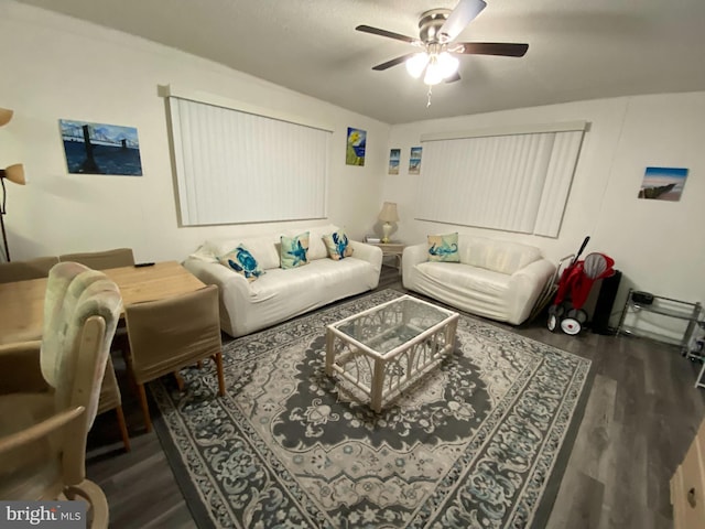 living room featuring ceiling fan and dark wood-type flooring