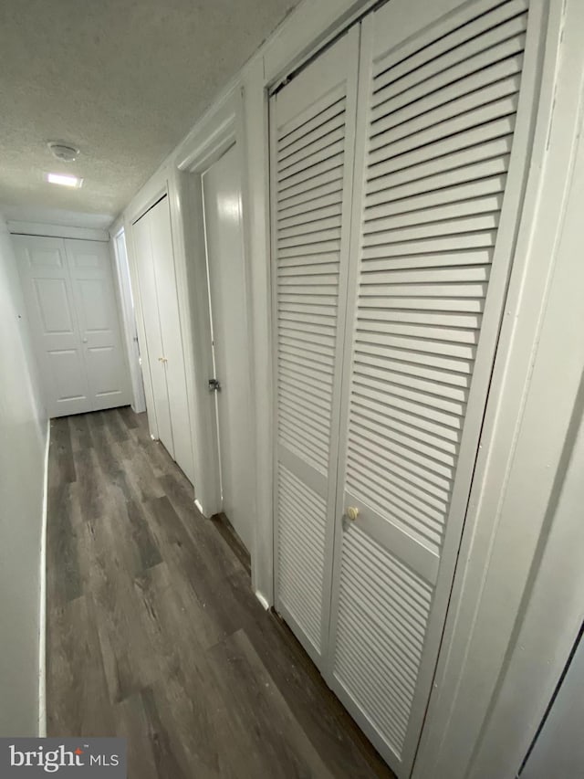 corridor featuring dark wood-type flooring and a textured ceiling