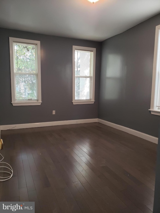 spare room with a healthy amount of sunlight and dark wood-type flooring