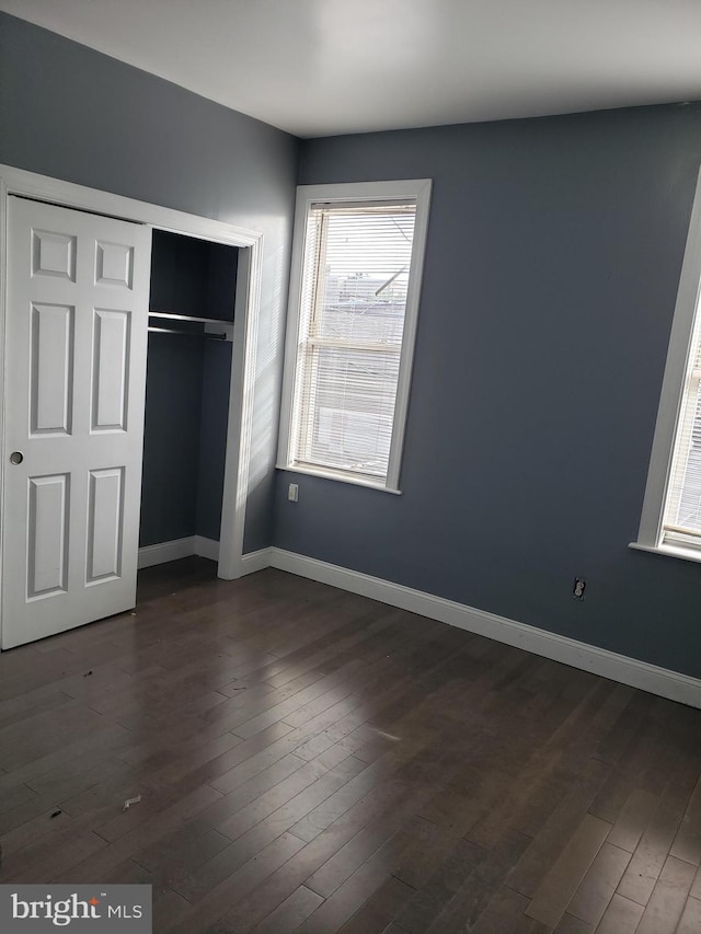 unfurnished bedroom featuring dark hardwood / wood-style flooring and a closet