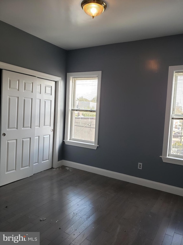 unfurnished bedroom with a closet and dark wood-type flooring