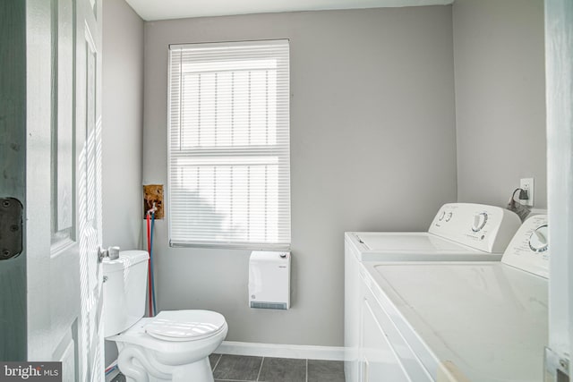 clothes washing area with dark tile flooring and independent washer and dryer