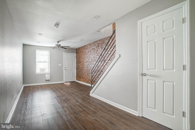 spare room featuring ceiling fan, brick wall, and dark hardwood / wood-style floors