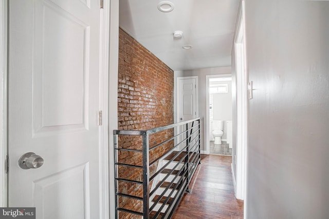 hallway with brick wall and dark wood-type flooring