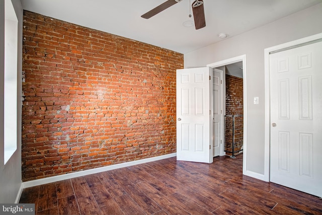 unfurnished bedroom with brick wall, ceiling fan, and dark hardwood / wood-style flooring