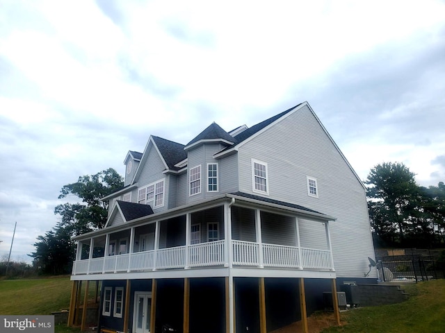 back of house featuring central air condition unit, covered porch, and a lawn