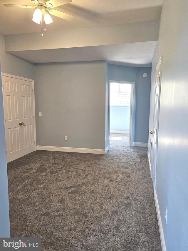 unfurnished room with ceiling fan and dark carpet