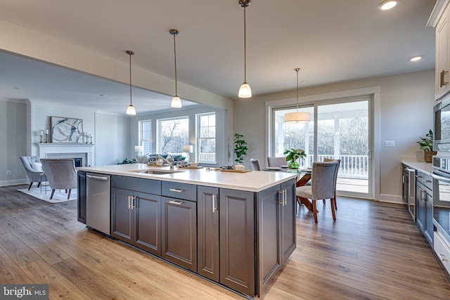 kitchen with decorative light fixtures, sink, stainless steel appliances, and light hardwood / wood-style flooring