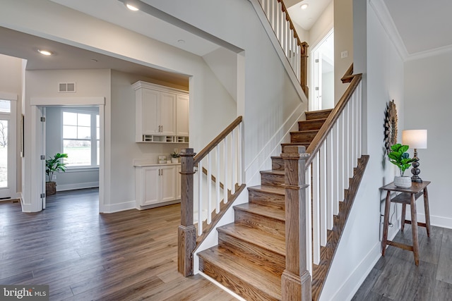 stairs featuring dark hardwood / wood-style flooring and ornamental molding