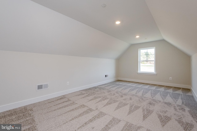 additional living space with light carpet and vaulted ceiling