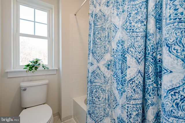 bathroom with toilet, a healthy amount of sunlight, and shower / bath combo