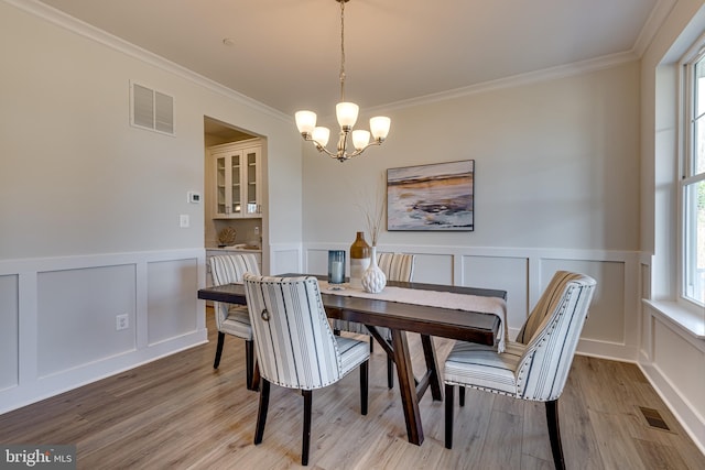 dining space featuring ornamental molding, a notable chandelier, and light hardwood / wood-style flooring