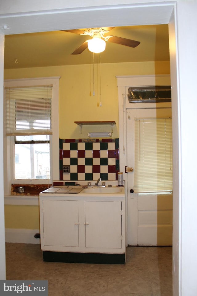 kitchen with backsplash, light tile floors, ceiling fan, and sink