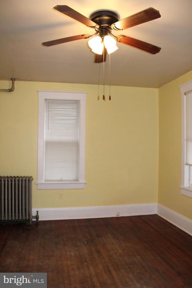 unfurnished room featuring dark hardwood / wood-style floors, ceiling fan, and radiator