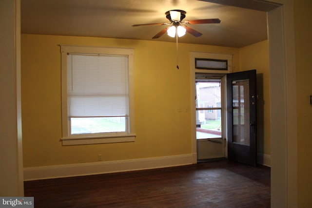 empty room with ceiling fan, dark hardwood / wood-style floors, and a wealth of natural light