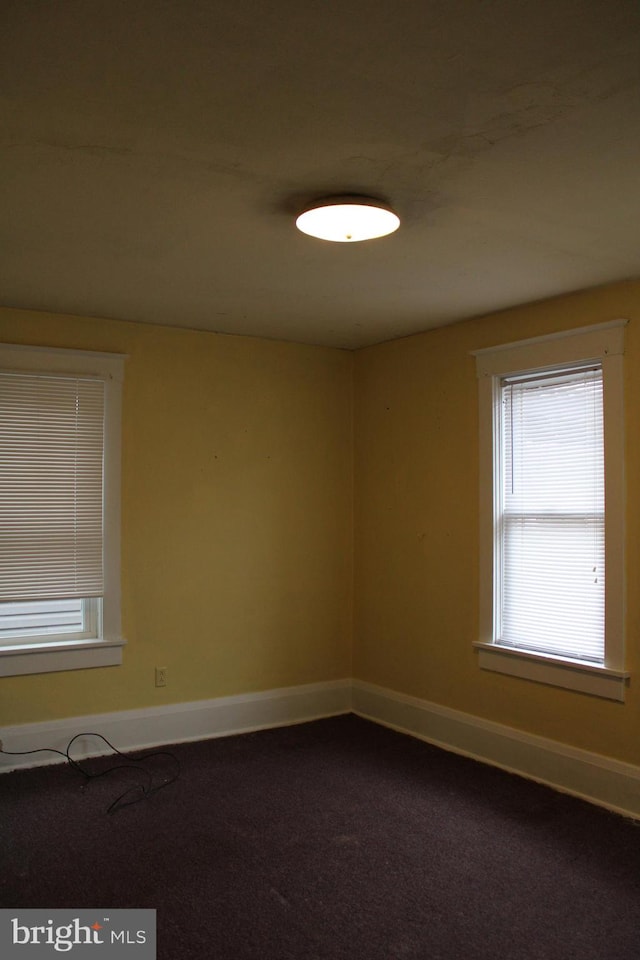 unfurnished room with dark carpet