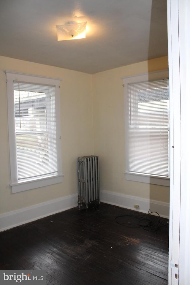 unfurnished room with dark wood-type flooring and radiator