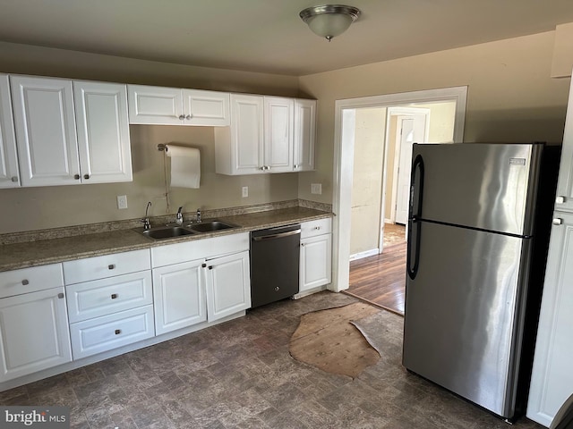 kitchen featuring white cabinetry, dark tile floors, appliances with stainless steel finishes, and sink