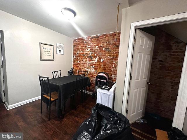 dining room featuring brick wall and dark hardwood / wood-style floors