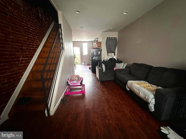 living room featuring brick wall and dark wood-type flooring