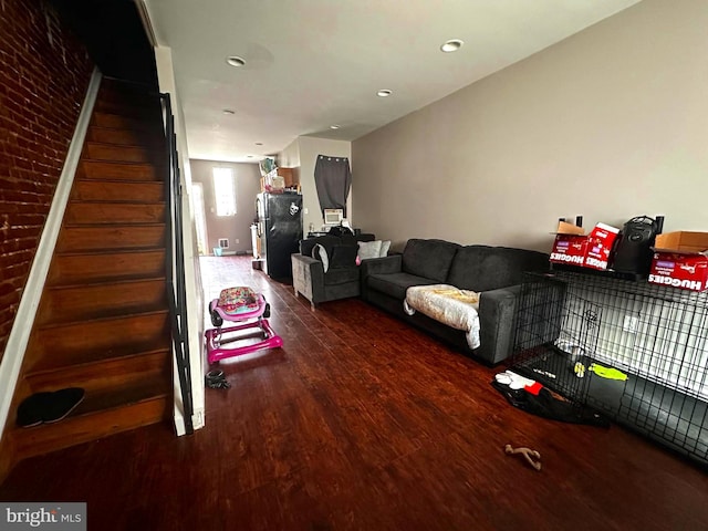 living room featuring dark hardwood / wood-style flooring and brick wall