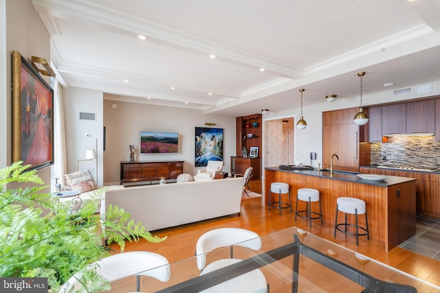 living room with crown molding, beam ceiling, sink, and light tile floors