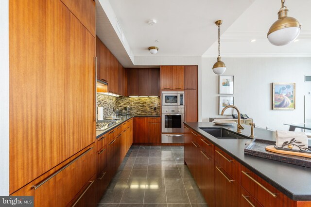 kitchen with decorative light fixtures, backsplash, appliances with stainless steel finishes, sink, and dark tile flooring