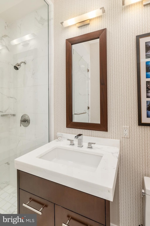 bathroom with a tile shower, oversized vanity, and toilet