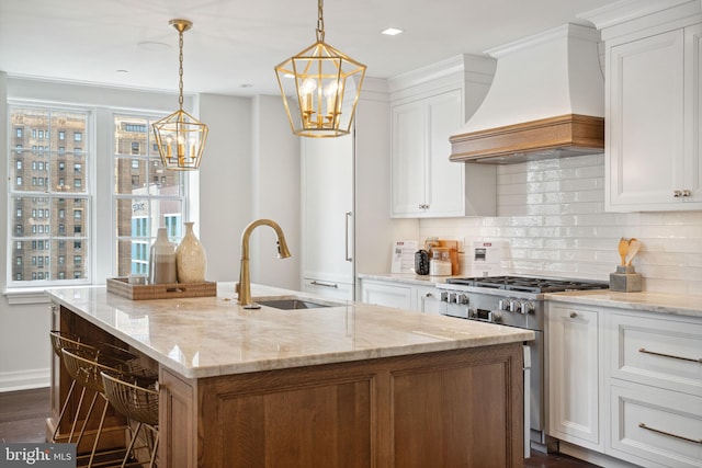 kitchen featuring an island with sink, light stone countertops, dark hardwood / wood-style flooring, custom range hood, and sink