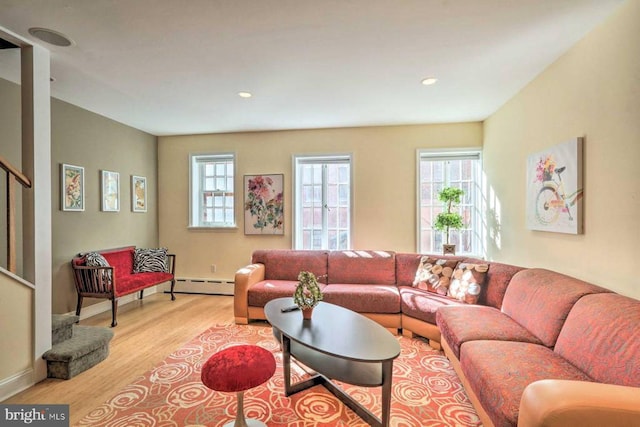 living room with a baseboard radiator, a wealth of natural light, and light wood-type flooring