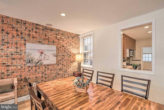 dining area featuring brick wall, hardwood / wood-style floors, and a wealth of natural light