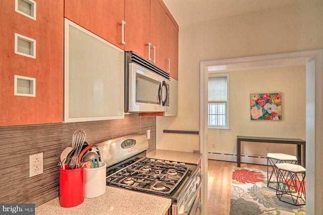 kitchen with backsplash, gas range, and light hardwood / wood-style floors